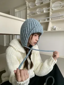 Detailed shot of a chunky knit balaclava earflap hat in light blue, showing texture.