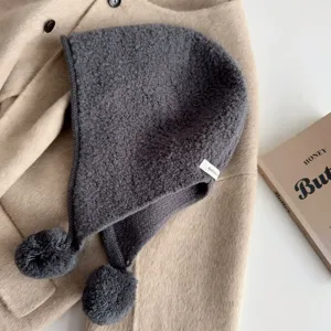 Grey knitted balaclava hat detail shot, pure wool material with cute pom poms for winter.