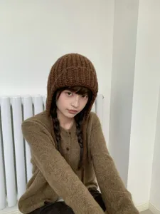 Detailed shot of a brown chunky knit balaclava hat, warm ear protection winter style.