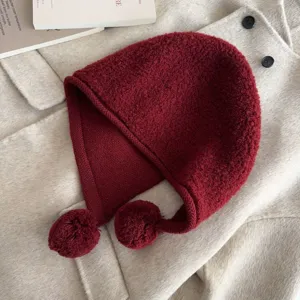 Detail view of the dark red knitted balaclava hat with cute dual pom-poms for winter cozy style.