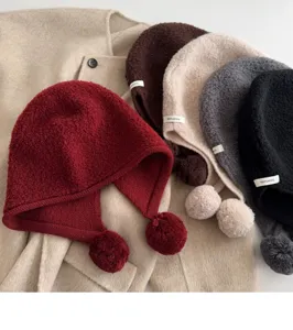 Close-up detail of knitted wool balaclava hats with cute pom-poms, soft winter texture.