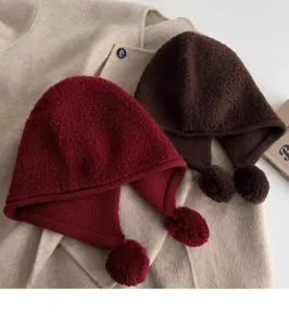 Close up detail of knitted wool balaclava hat with cute pom poms in winter style.