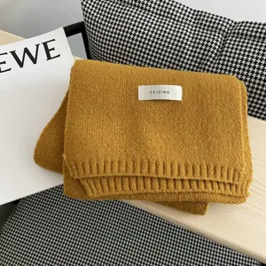 Detalle de bufanda de lana tejida amarilla con etiqueta, accesorio de invierno elegante.