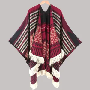 Detailed view of the ethnic style knitted cape with geometric patterns and fringe hem.
