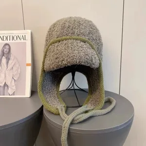 Nahaufnahme der grauen Plüsch-Trappermütze Detail, warme Wintermütze mit grünem Strickrand.