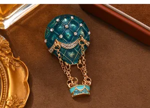 Close-up detail of the vintage green enamel hot air balloon brooch, rhinestones, gold chains.