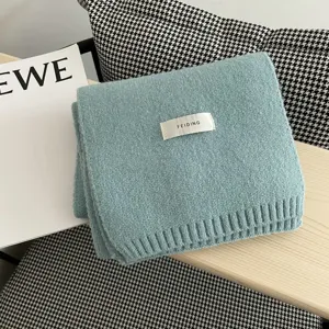 Detalle de bufanda de invierno de punto suave en azul claro con etiqueta de marca.