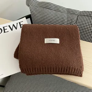 Detalle bufanda de punto marrón invierno, textura de lana suave con etiqueta, cálida