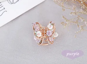 Detail shot of a cute polymer clay rose butterfly hair claw clip with sparkly rhinestones.