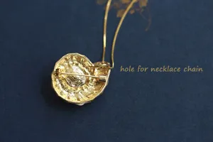Gedetailleerd achteroverzicht van vintage schelp broche met speld en kettinggat.