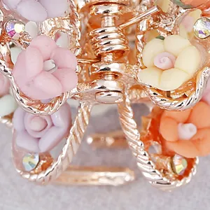 Close-up of vintage alloy hair claw clip with soft clay roses and sparkling rhinestones.