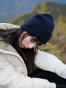 Close-up detail of the cozy dark blue wool knit beanie worn outdoors, soft warm texture.