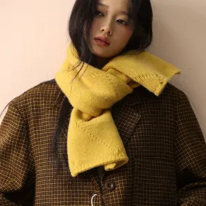 Detaillierte Nahaufnahme eines kuscheligen gelben Strickschals mit stilvollem Knopf-Design.