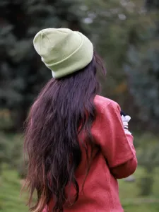 Detailed view of a stylish solid green knitted beanie hat for outdoor autumn and winter wear.