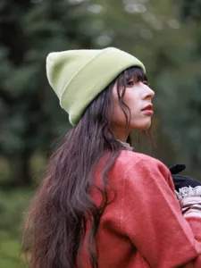 Green knit beanie hat detail view, soft warm wool winter cap for women outdoor travel style.