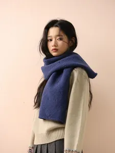 Detailaufnahme eines weichen blauen Strickschals am Model, der Textur und Winterwaerme zeigt.