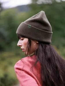 Close-up detail of the dark green wool knit beanie cuff and texture, winter outdoor style.