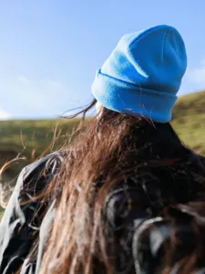 Outdoor solid color cuffed knit beanie warm wool winter hat detail shot against sky view.