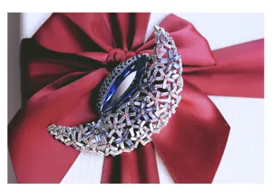 Close-up detail of vintage crystal moon brooch with deep blue rhinestones on red ribbon gift box.