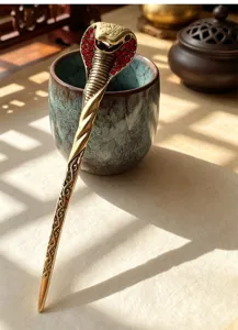 Close-up detail of vintage cobra hairpin with red rhinestones, elegant accessory styling.