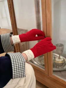 Detailed view of cozy red knitted gloves with white cuffs, perfect for winter warmth.