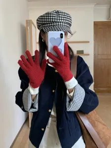 Close-up detail of the vibrant red knitted winter gloves featuring contrasting white ribbed cuffs.