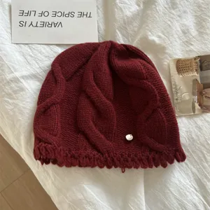 Close-up view of the cozy wool cable knit beanie hat texture in burgundy winter style.