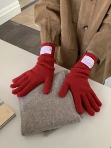 Rote Strickhandschuhe mit weißem Logolabel, gemütliches Winter Accessoire Detail.