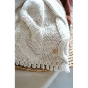 Close-up detail of cozy cable knit wool beanie showcasing soft texture and delicate metal tag.
