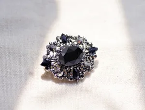 Primo piano di una spilla vintage in stile barocco con gemma nera e brillanti strass.