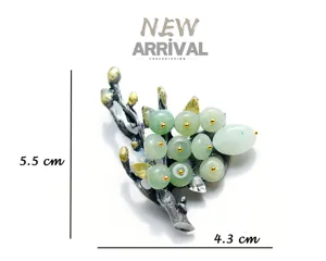 Detailed view of vintage plant branch brooch with green jade berries and silver metal.