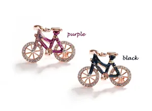 Detail shot of the creative bicycle brooch featuring rhinestone wheels and elegant metal frame.