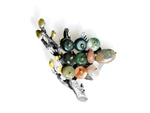 Close-up of vintage style branch brooch with colorful agate stone clusters and textured silver.