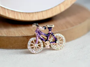 Close-up detail view of a vintage bicycle brooch with sparkling crystals and enamel.