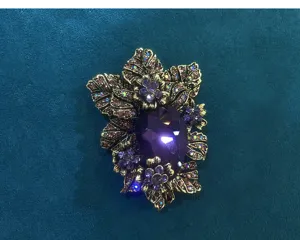 Vintage crystal glass brooch featuring a deep purple teardrop stone and detailed floral rhinestones.