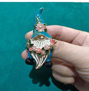 Close-up detail of a charming enamel gnome brooch with floral decoration and bright colors.