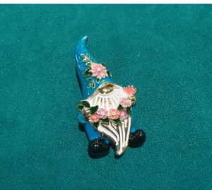 Enamel gnome brooch close-up with floral design and vibrant colors for clothing decor.
