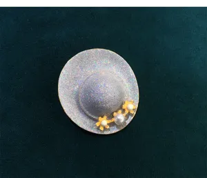 Vintage sparkling hat brooch detail view, featuring delicate flower and white pearl accessory.