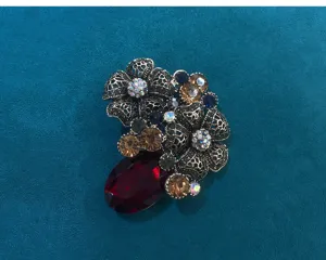 Detailed vintage crystal floral brooch close-up, antique gold filigree and colorful rhinestones.