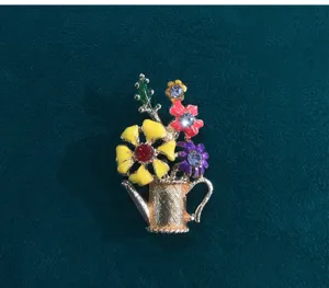 Detailed view of vintage watering can flower brooch, colorful enamel pin for fashion clothing.