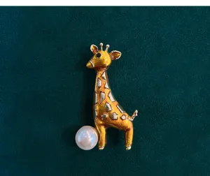 Charming giraffe brooch detail featuring gold-tone finish and delicate pearl accent. Perfect gift.
