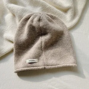 Primer plano detallado del acogedor gorro de lana tejido en color beige con textura y etiqueta.