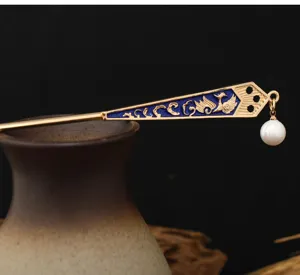 Gros plan sur un épingle à cheveux traditionnelle chinoise dorée avec émail bleu et perle.