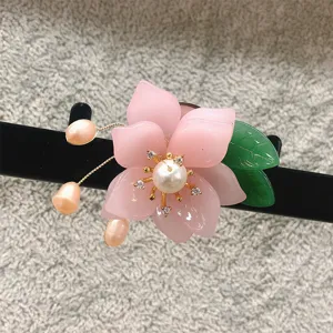 Close-up of pink imitation glazed flower brooch with pearl and crystals for vintage outfits.