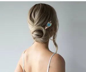 Close-up detail of retro blue enamel rhinestone peacock feather hairpin worn in a chic bun.