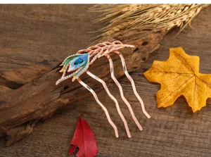 Detail view of a retro rose gold peacock feather hair comb with rhinestones and colorful enamel.