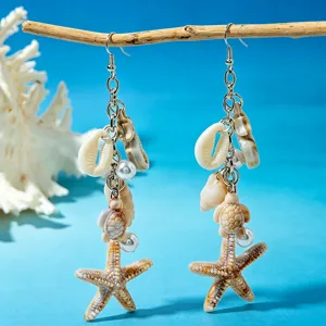 Close-up of beach-style shell and starfish drop earrings on ocean blue background