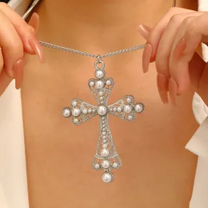 Detailansicht der verzierten silbernen Kreuzkette mit eleganten weißen Perlen