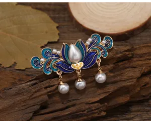 Détail de pince à cheveux vintage en émail avec fleurs, pampilles de perles et métal doré élégant.