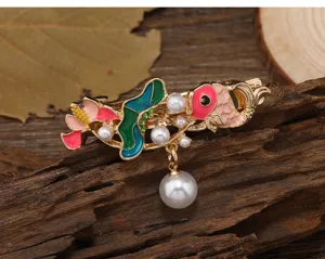 Vue détaillée de la pince à cheveux rétro émaillée poisson rouge perle, design oriental.